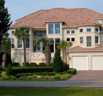 A large house with a driveway and bushes around it.